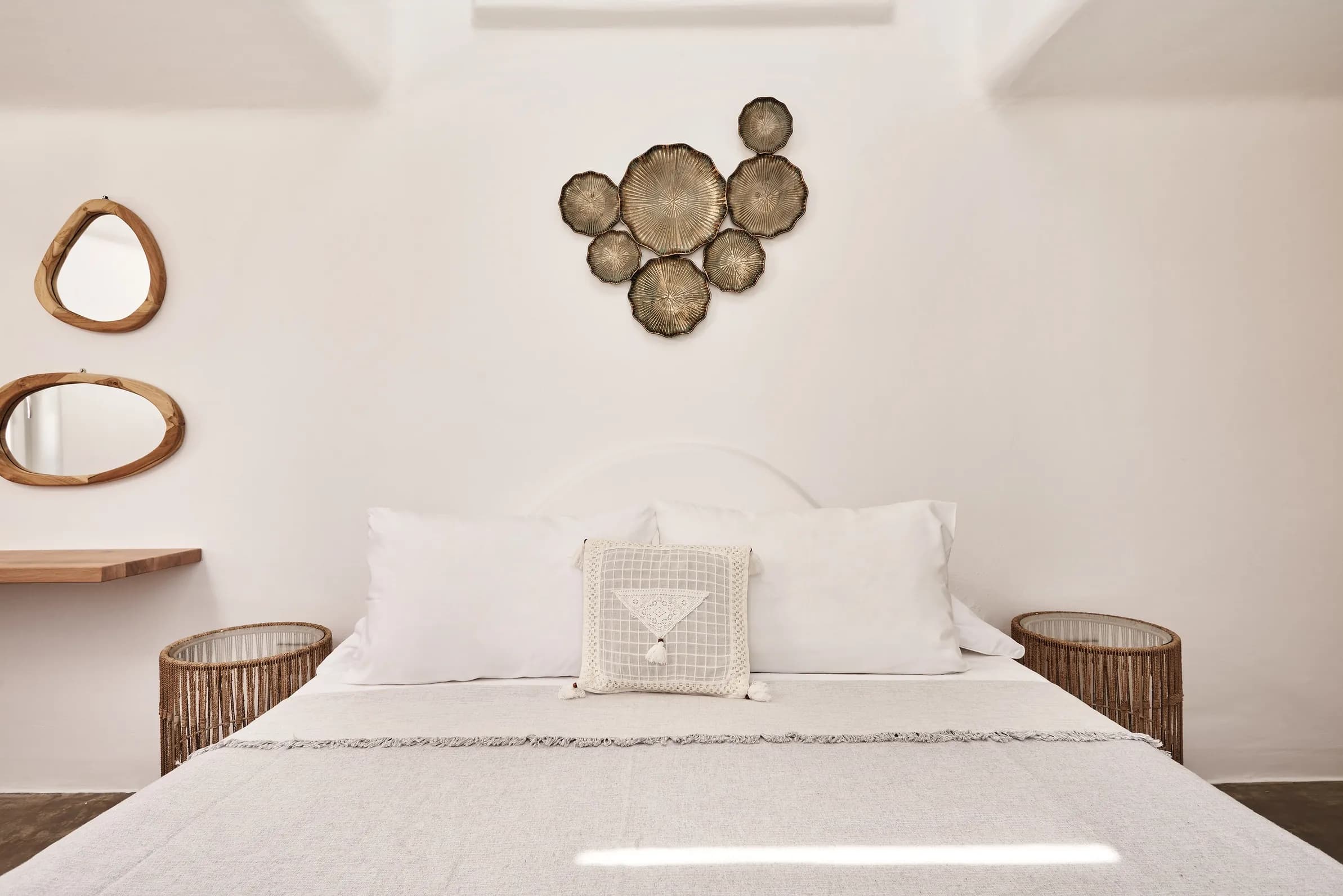 Double bed with white linen beneath woven wall decorations