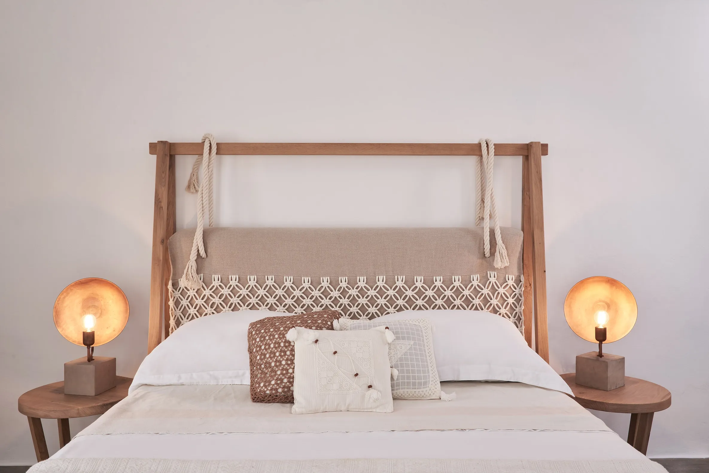 Double bed with a wooden frame, embroidered cushions and two copper lamps