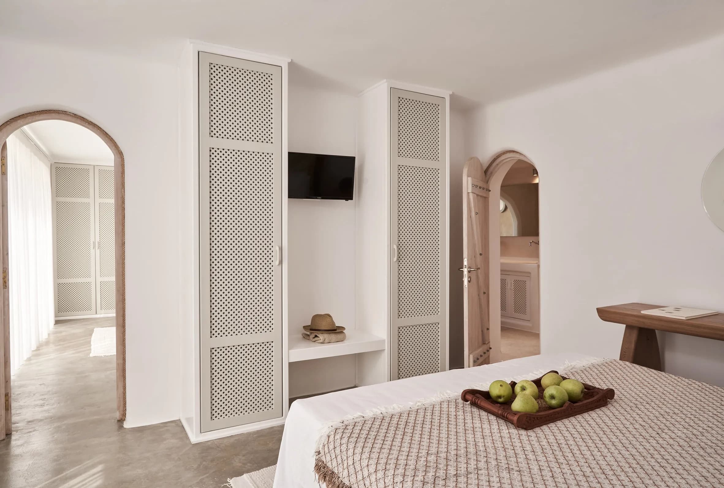 Bedroom with an arched doorway, latticed wardrobes and a wall-mounted TV